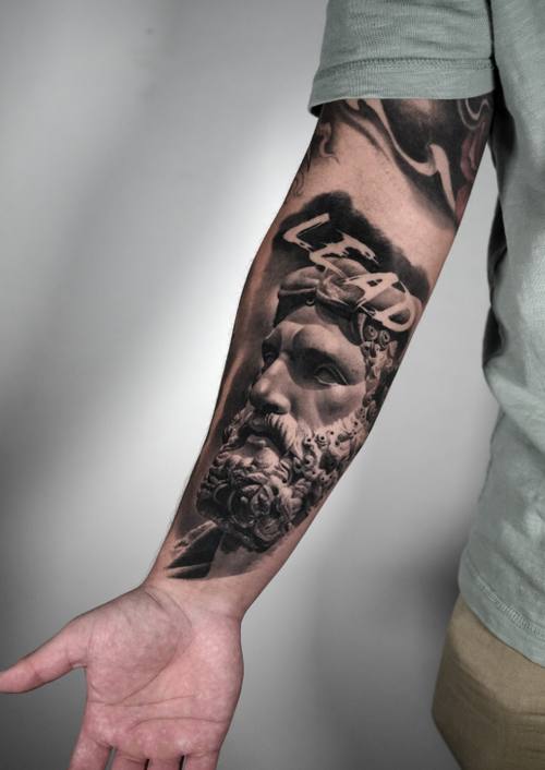 Bearded classical statue with LEAD lettering, black and grey forearm tattoo