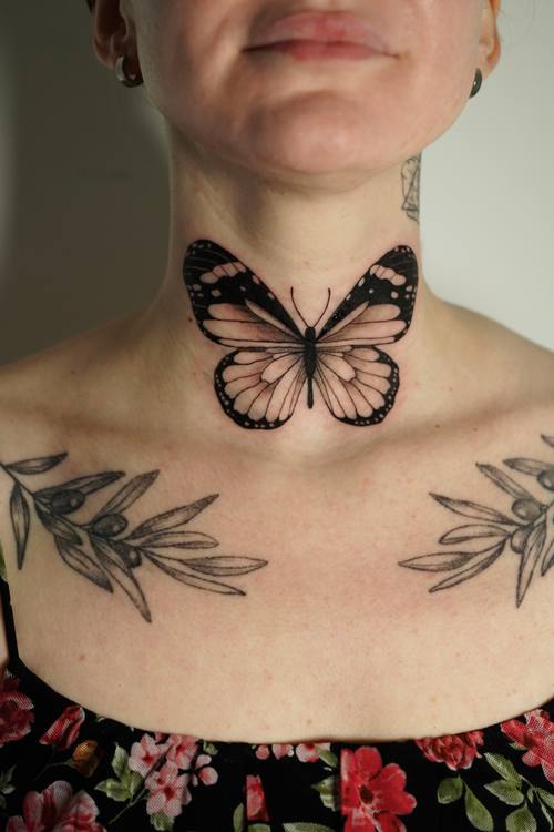 Butterfly on the throat with botanical work across the collarbones, fine line tattoo by Amina at KAZENTATTOO, Los Angeles