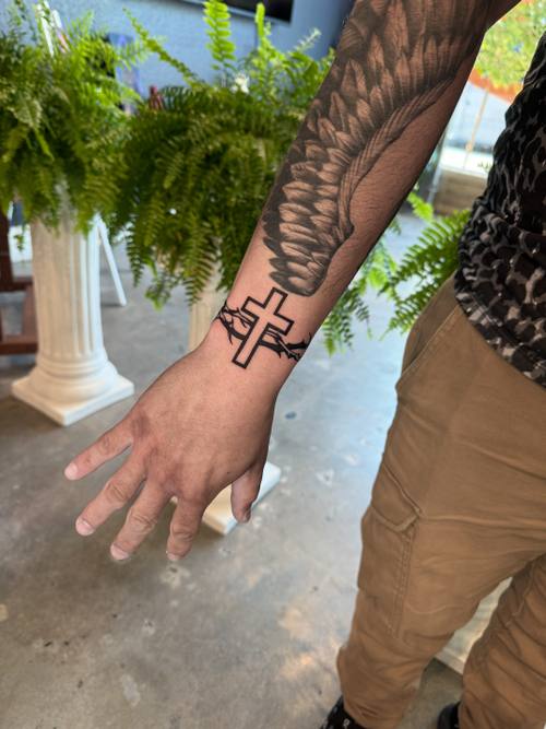 Cross on the hand with a botanical sleeve, fine line tattoo by Amina at KAZENTATTOO, Los Angeles