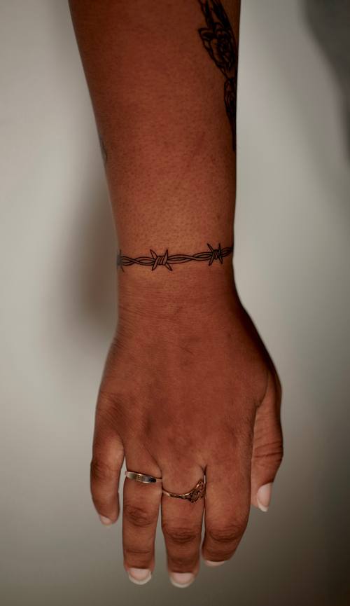 Thin band bracelet around the wrist, fine line tattoo by Amina at KAZENTATTOO, Los Angeles