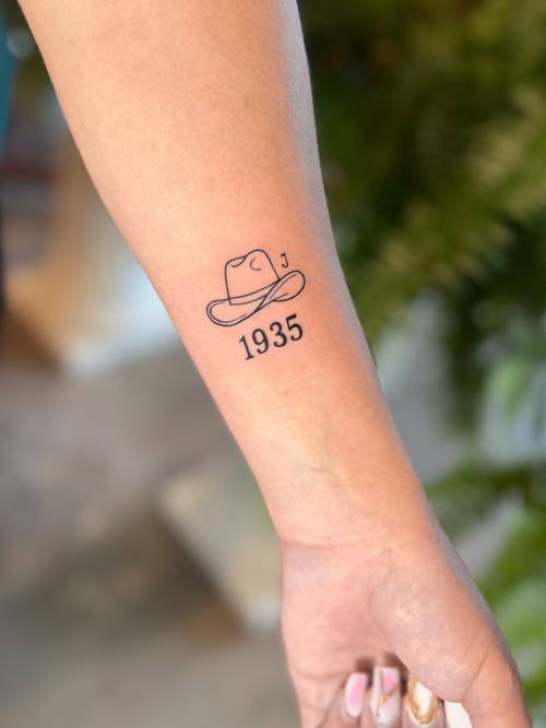 Cowboy hat with numerals on the forearm, fine line tattoo by Amina at KAZENTATTOO, Los Angeles