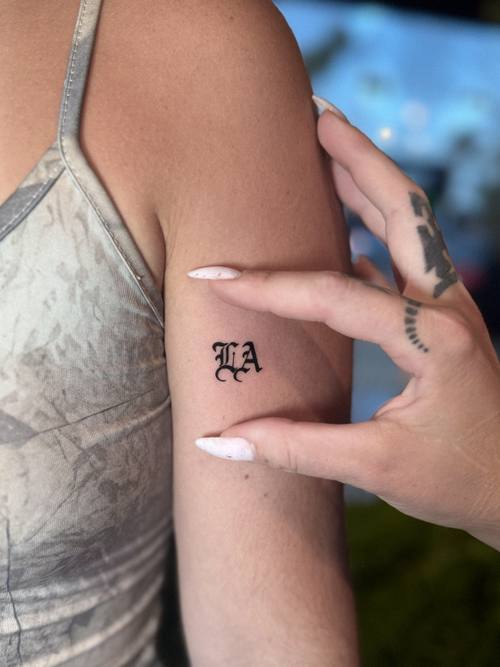 Small lettering on the upper arm, fine line tattoo by Amina at KAZENTATTOO, Los Angeles