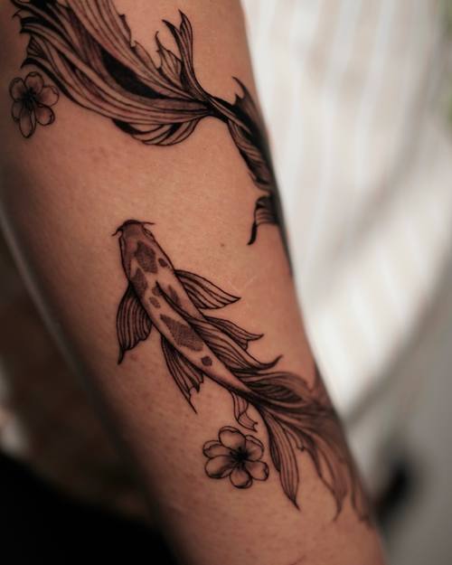 Koi fish with flowers on the upper arm, fine line tattoo by Amina at KAZENTATTOO, Los Angeles
