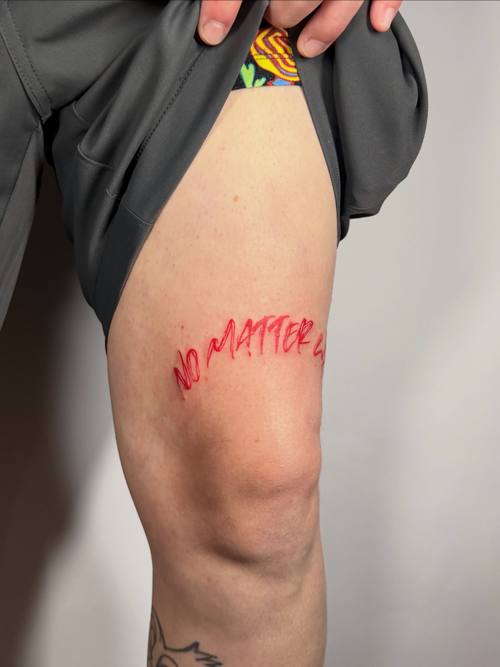 Script in red ink on the thigh by Amina at KAZENTATTOO, Los Angeles