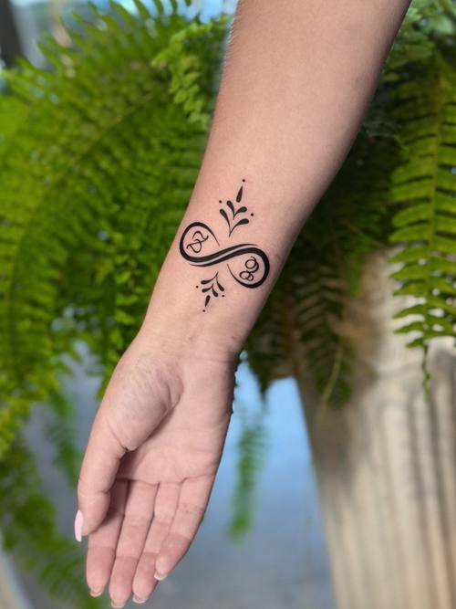 Looped symbol with script on the wrist, fine line tattoo by Amina at KAZENTATTOO, Los Angeles
