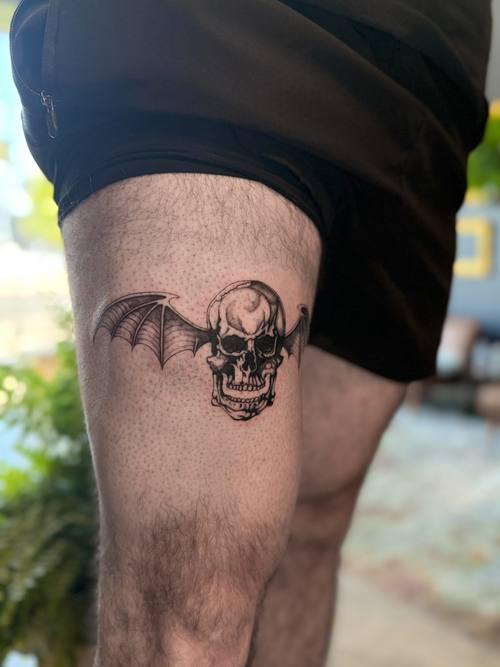 Winged skull on the thigh in close view, black and grey tattoo by Amina at KAZENTATTOO, Los Angeles