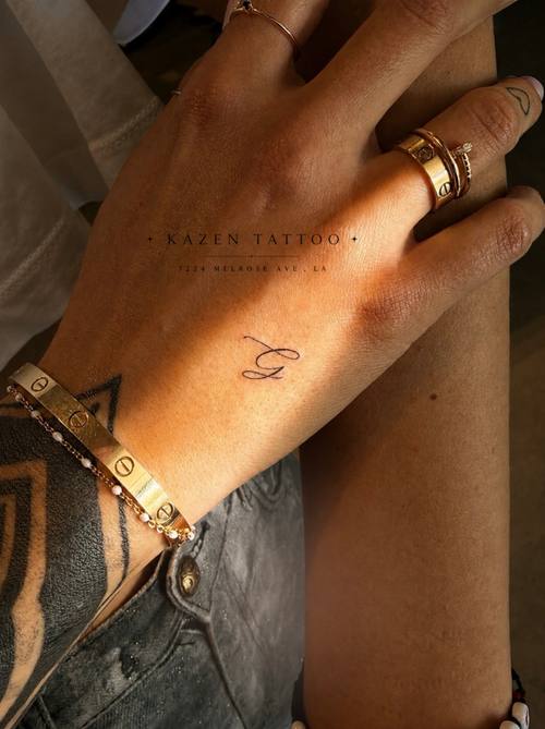 Small fine line symbol on the back of the hand by Amina at KAZENTATTOO, Los Angeles
