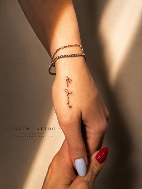 Script lettering along the side of the hand, fine line tattoo by Amina at KAZENTATTOO, Los Angeles