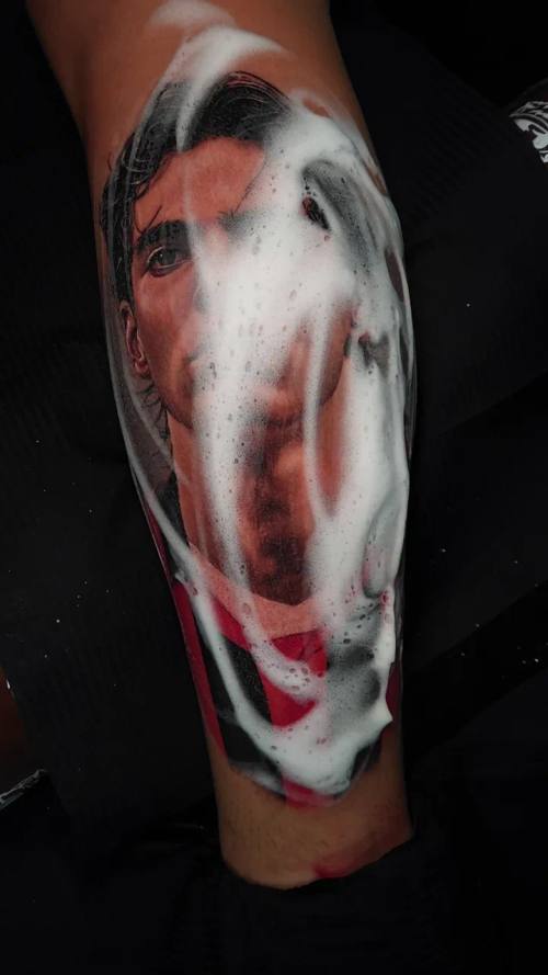 Distorted white-painted horror face, colour realism calf tattoo by Livio at KAZENTATTOO, Los Angeles