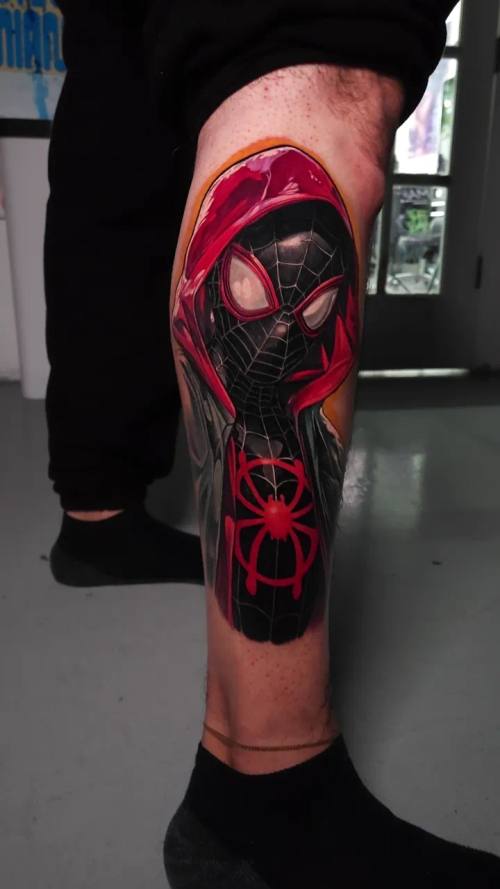 Masked superhero with a spider emblem, colour realism calf tattoo by Livio at KAZENTATTOO, Los Angeles