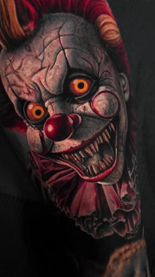 Grinning horror clown in close-up, colour realism arm tattoo by Livio at KAZENTATTOO, Los Angeles