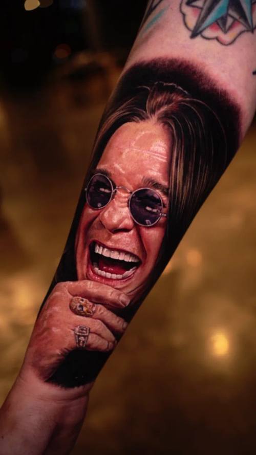 Rock musician in round sunglasses, colour realism arm tattoo by Livio at KAZENTATTOO, Los Angeles