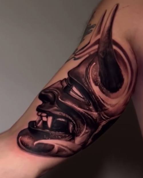 Hannya mask in close-up, black and grey realism arm tattoo by Nihat at KAZENTATTOO, Los Angeles