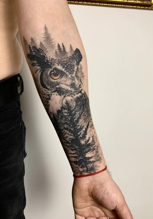 Black and grey owl with an orange accent, trees and moon on the forearm by Padre at KAZENTATTOO, Los Angeles