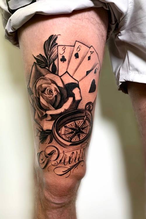 Black and grey playing cards, rose, compass and script on the thigh by Padre at KAZENTATTOO, Los Angeles