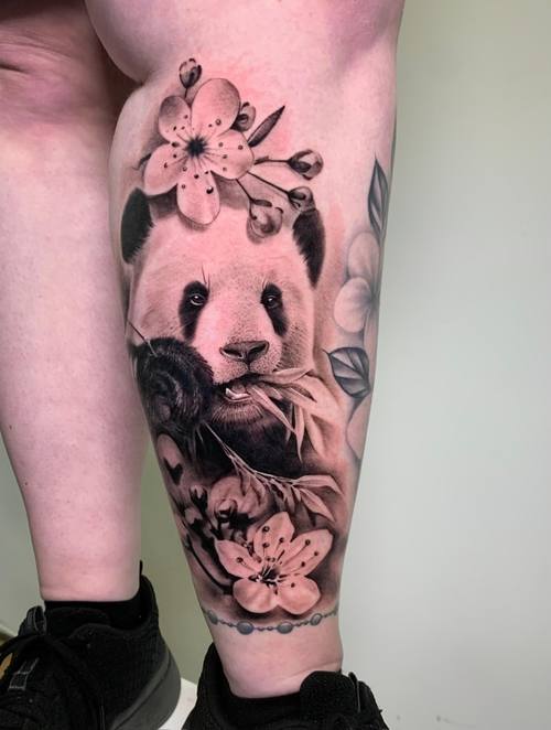 Black and grey panda with cherry blossoms and roses on the lower leg by Padre at KAZENTATTOO, Los Angeles
