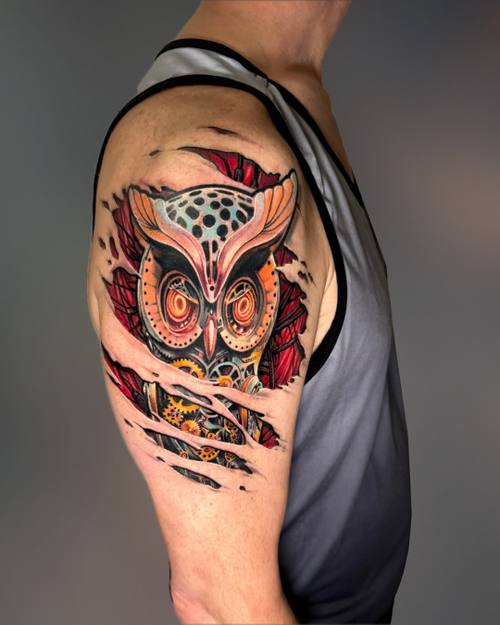 Surreal color mechanical owl bursting through ripped skin on the shoulder by Padre at KAZENTATTOO, Los Angeles