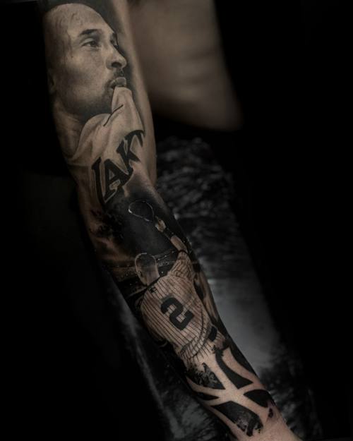 Portrait of a man looking upward with a basketball jersey, black and grey forearm sleeve by Sam at KAZENTATTOO, Los Angeles