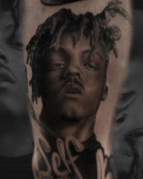 Portrait of a young man with dreadlocks and lettering, black and grey arm tattoo by Sam at KAZENTATTOO, Los Angeles