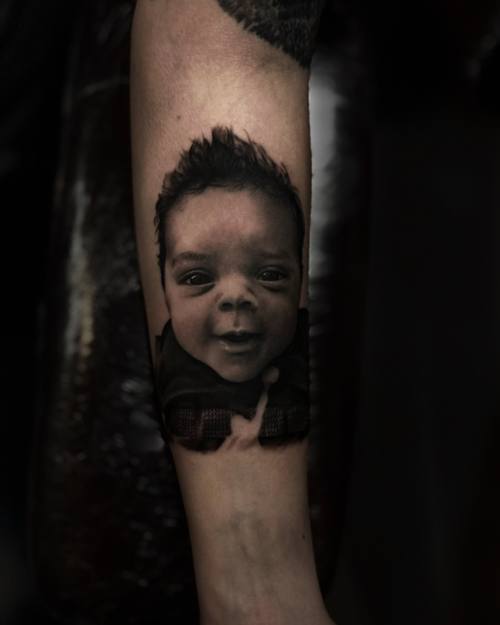 Portrait of a laughing baby, black and grey realism forearm tattoo by Sam at KAZENTATTOO, Los Angeles