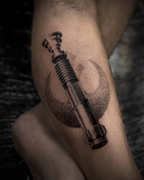 Lightsaber with a rebel emblem, dotwork black and grey calf tattoo by Sam at KAZENTATTOO, Los Angeles