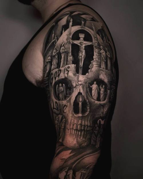 Skull with crucifix and cathedral inside, black and grey upper arm tattoo