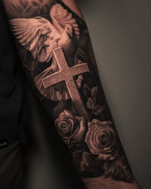 Winged cross with roses, black and grey realism arm tattoo