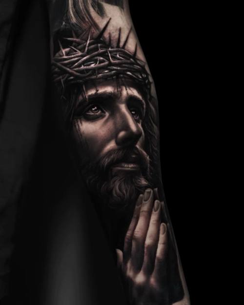 Jesus with crown of thorns and praying hands, black and grey arm tattoo