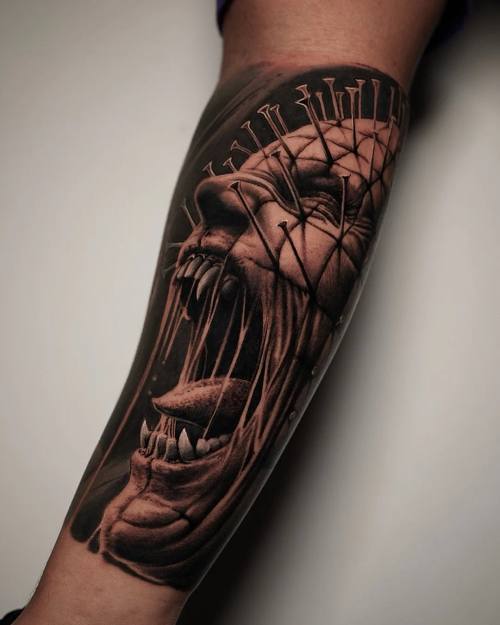 Demon head with nails, black and grey realism forearm tattoo