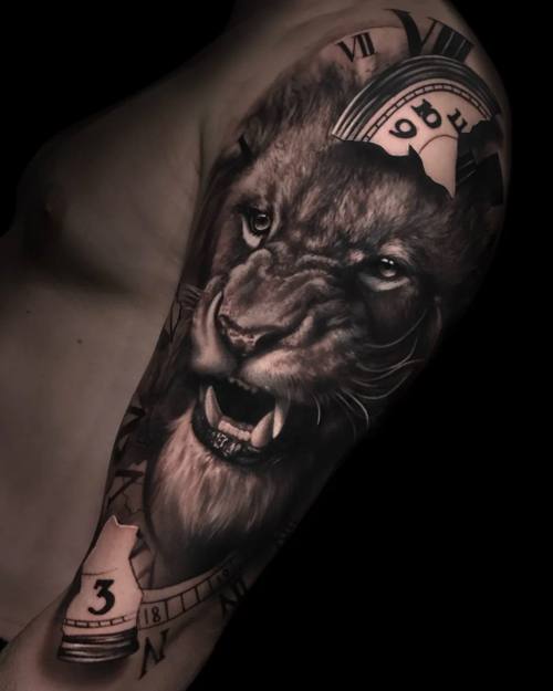 Roaring lion with playing cards, black and grey realism upper arm tattoo by Vladimir Kozachenko