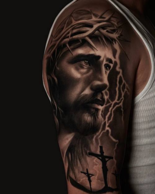 Jesus with crown of thorns and three crosses, black and grey upper arm tattoo